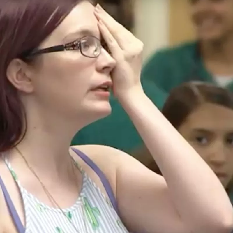 A woman doing an eye test as she covers one of her eyes and reads letters