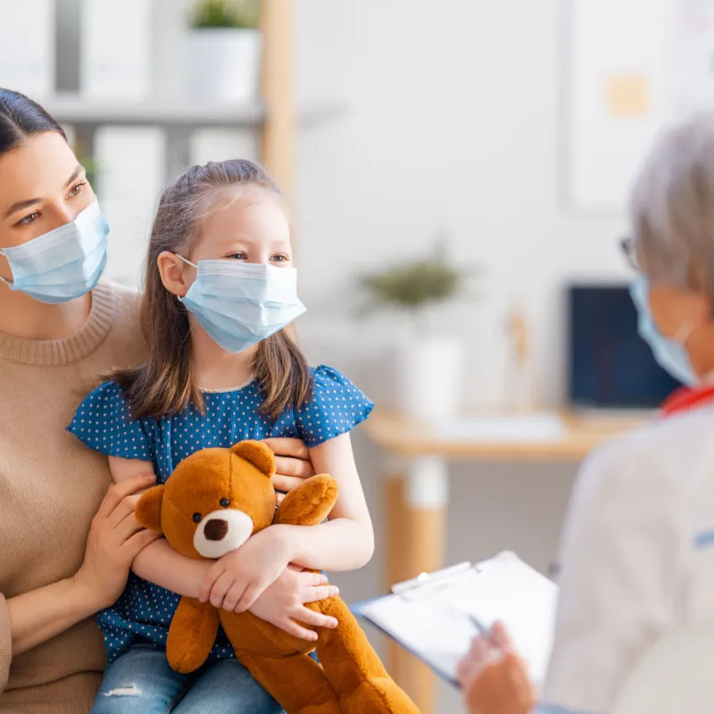 A mother and daughter talking face-to-face with a doctor