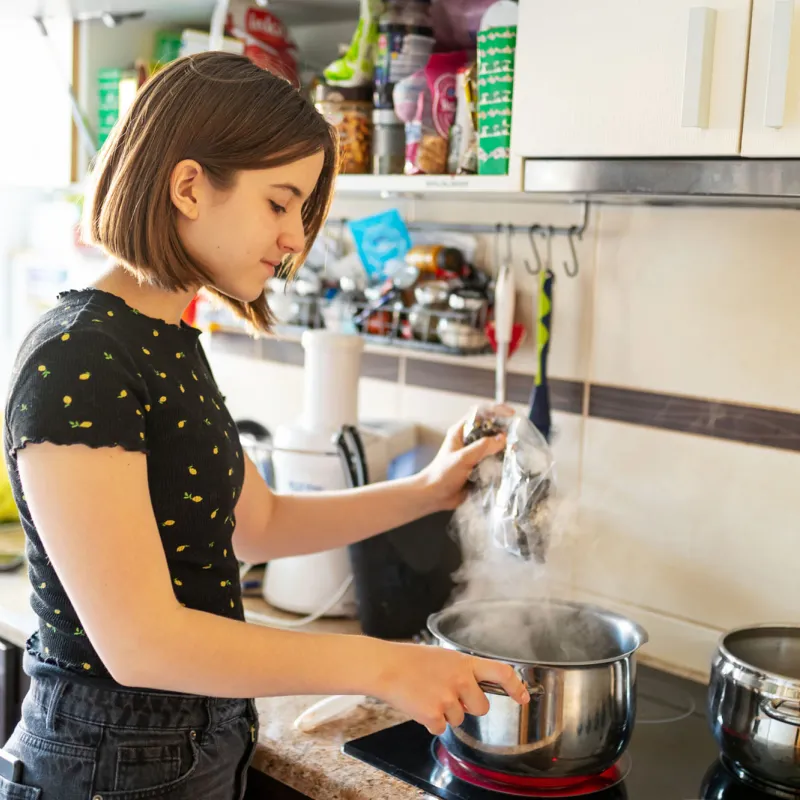 A young lady using her stove in the kitchen