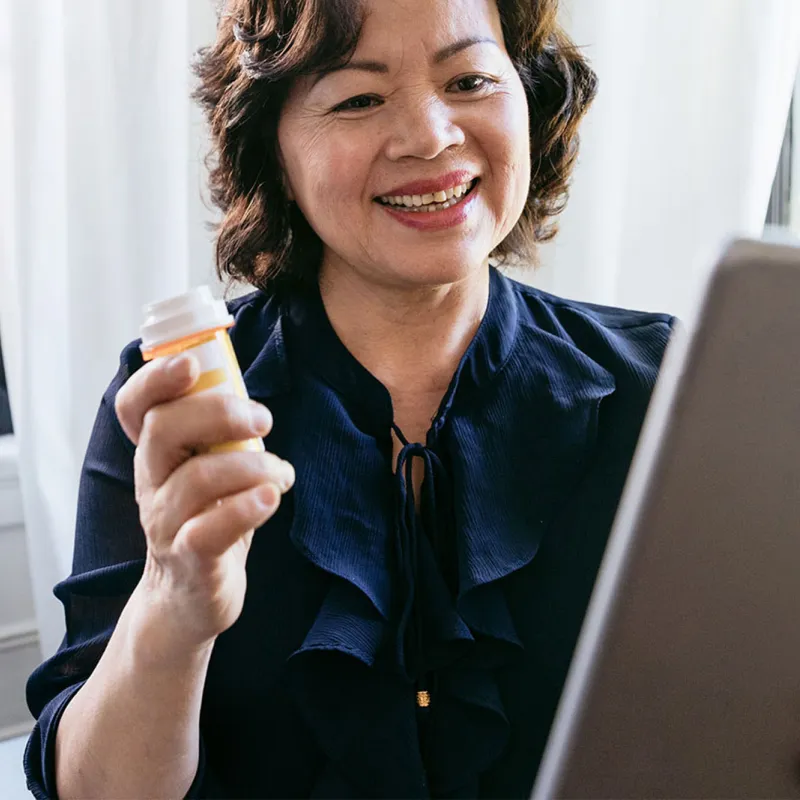 A woman holding a tablet and talking to her doctor about her prescription on a video call.