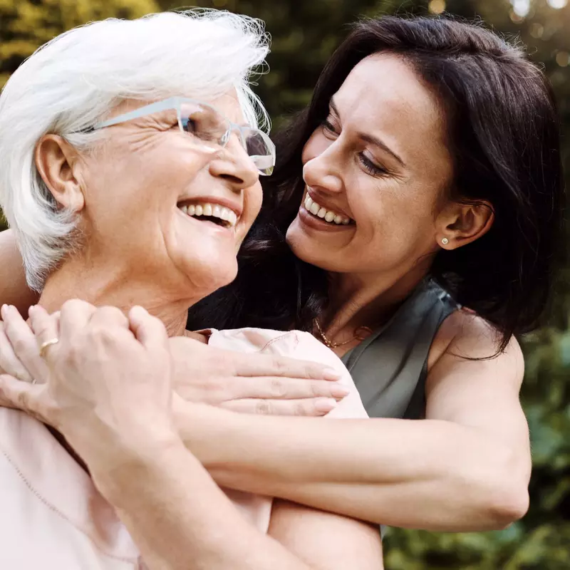 An adult woman hugs her mother.