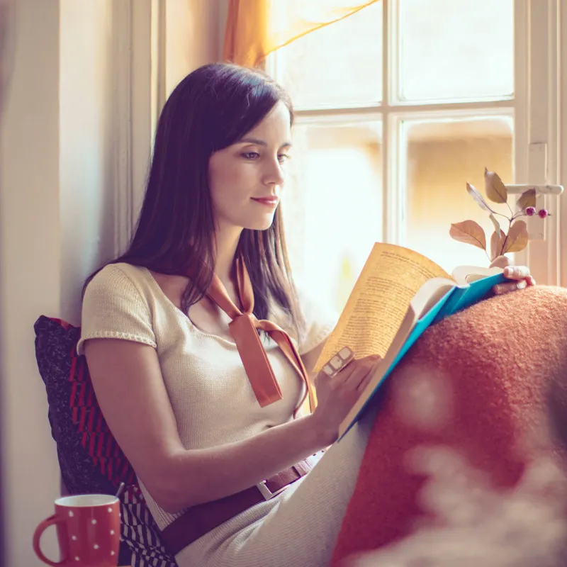 Woman reading near a window.