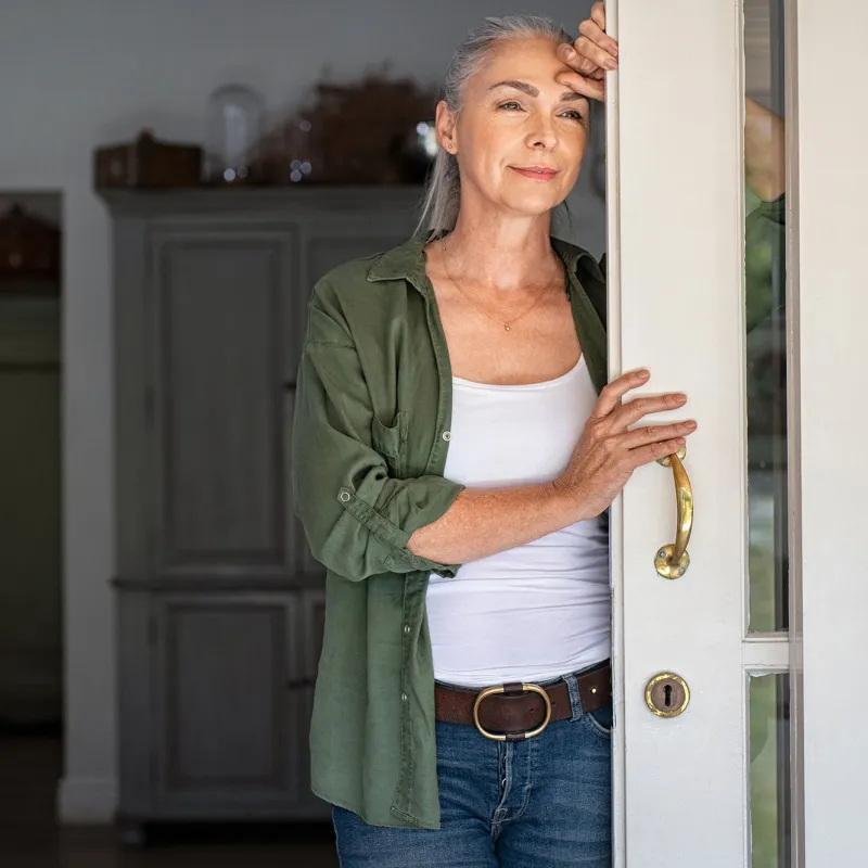 A woman standing by her doorway.