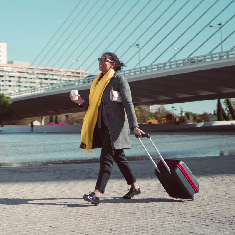 A young woman rolls her suitcase as she travels