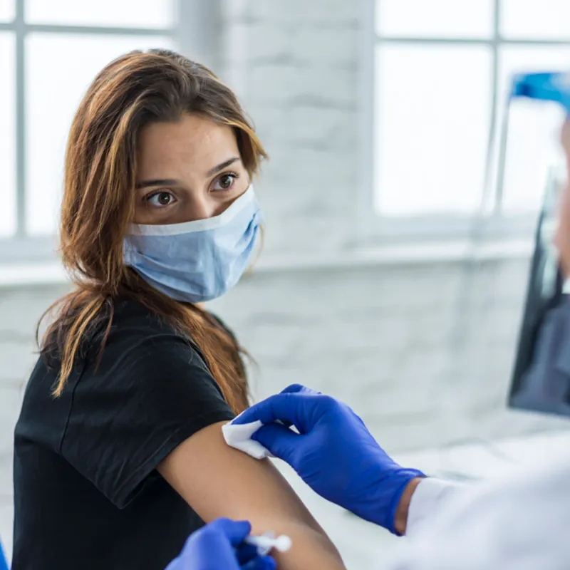 Woman wearing a mask getting her covid-19 vaccine booster shot.