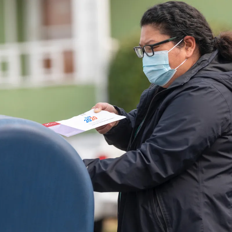 A woman dropping in her 2020 mail-in ballot