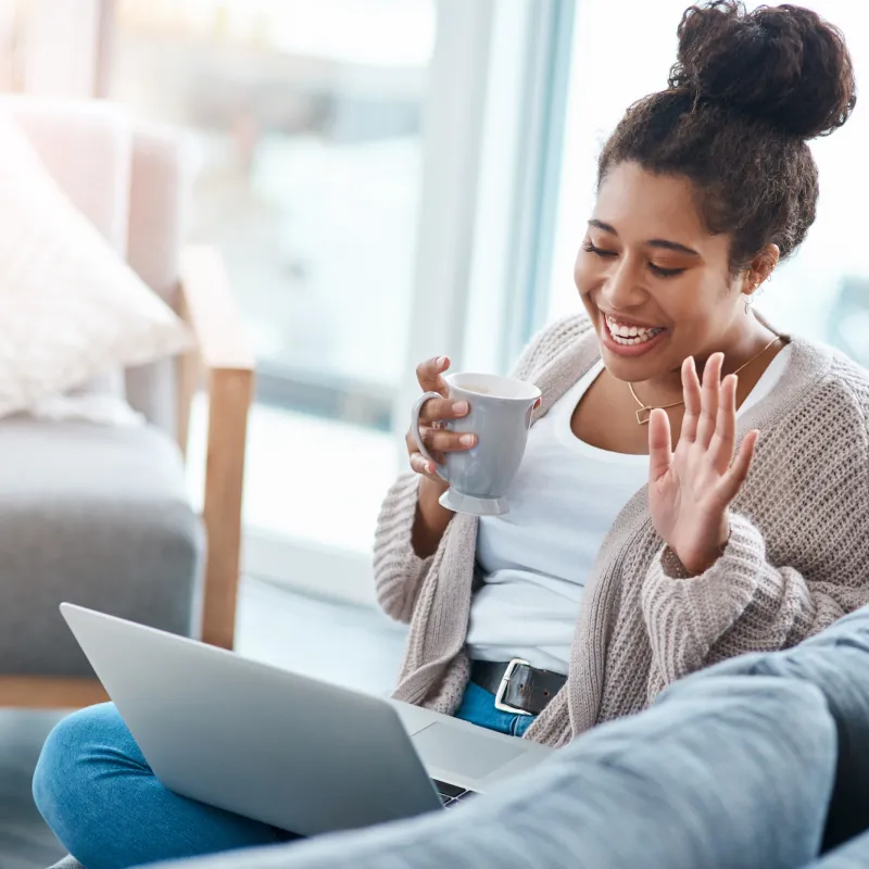 A woman waving to a friend on a video call. 