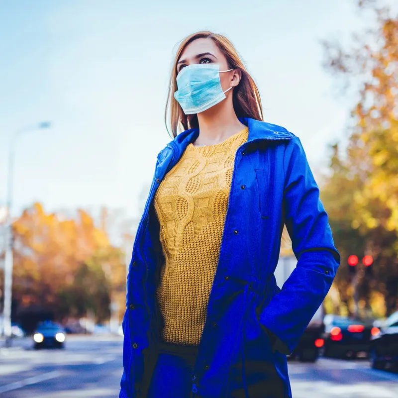 A woman wearing a mask outside. 