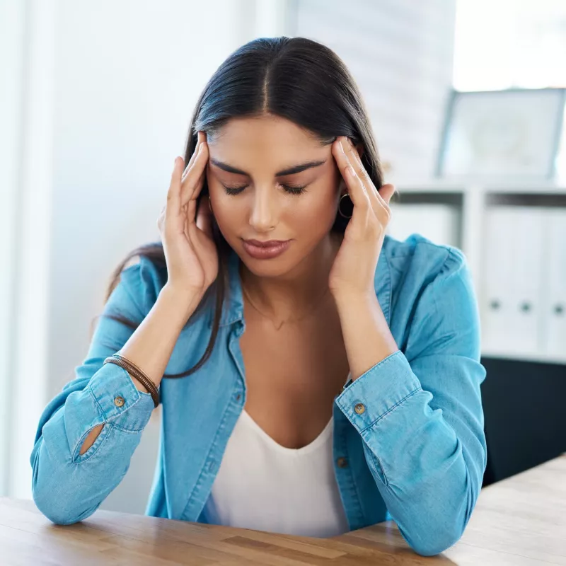 A woman with a headache massaging her temples.