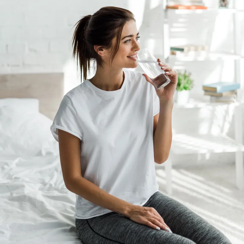 A young woman drinking a glass of water.