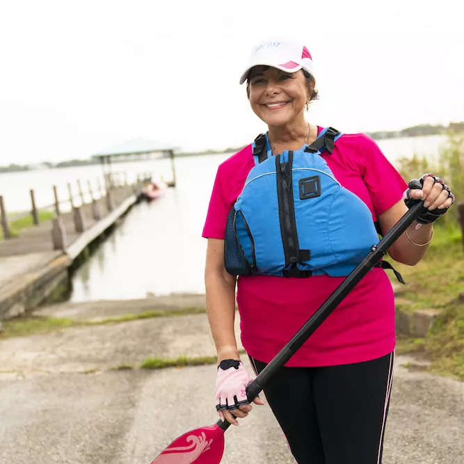 Woman wearing a life vest and holding a boating paddle