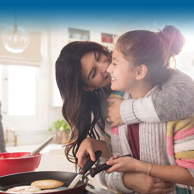 mother-cooking-and-hugging-her-daughter