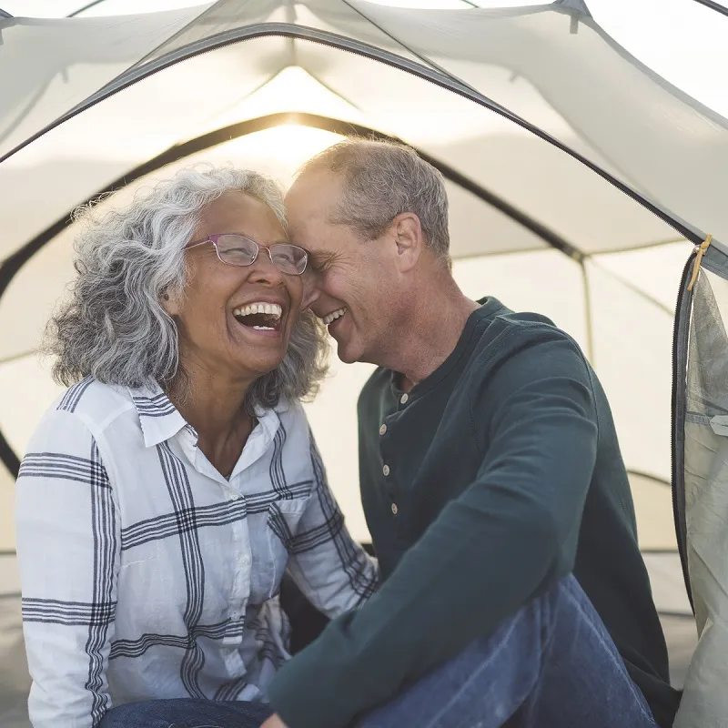 man and woman camping in tent with sun shining