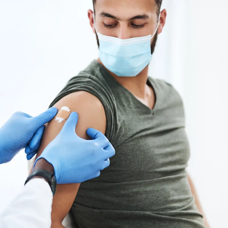 Man getting bandaged after a vaccine while wearing a mask.