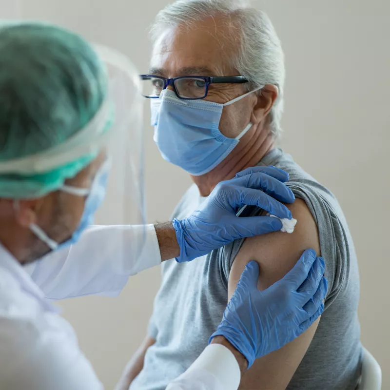 Man getting bandaged after a vaccine while wearing a mask.