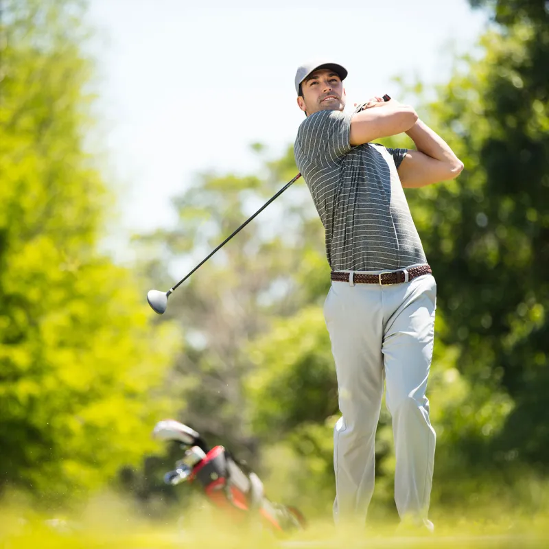 A man playing golf on the golf course on a sunny day.