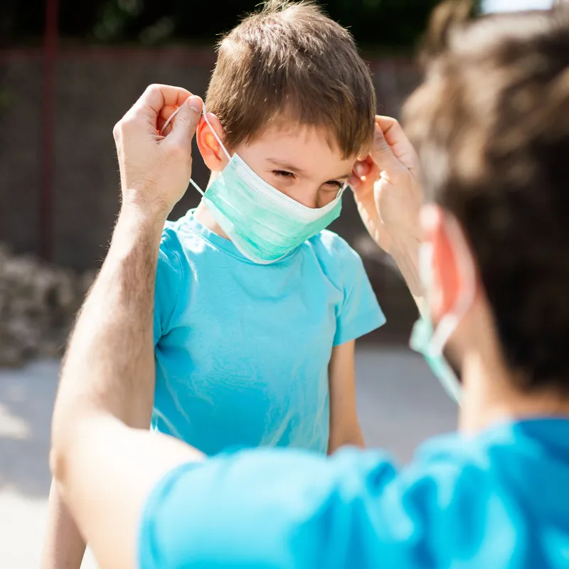 A father puts a mask on his young son.