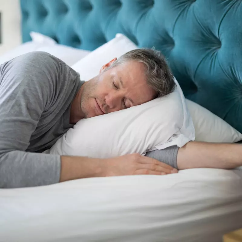 Man sleeping on his side in a bed.