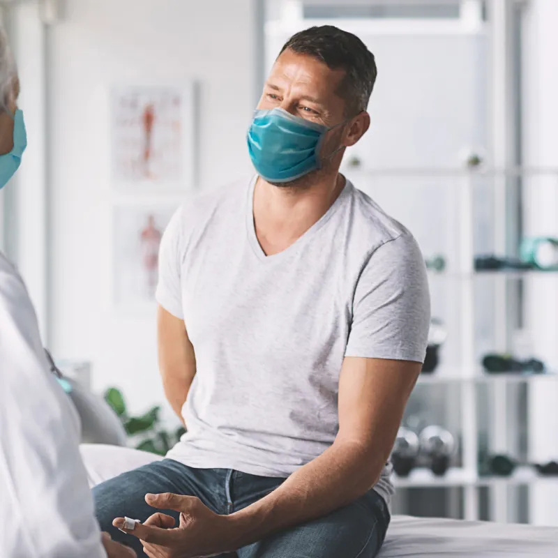 Man talking with talking while both are wearing masks.