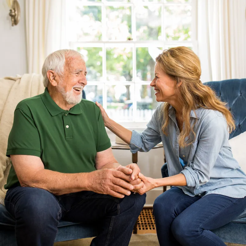 A daughter having a conversation with her elderly father in the family room.