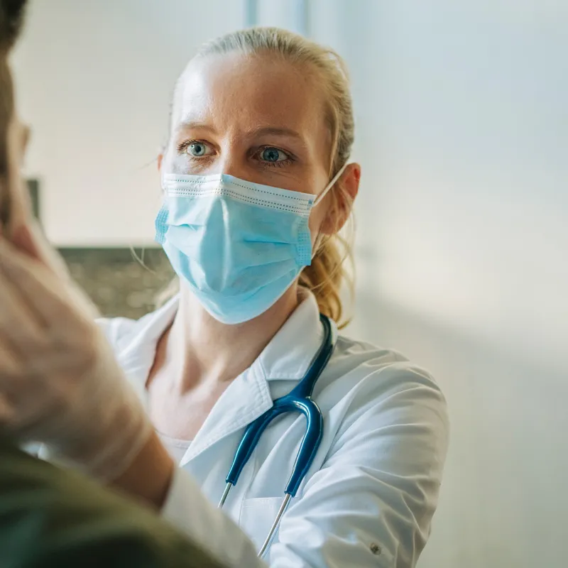 Masked physician examining patient.