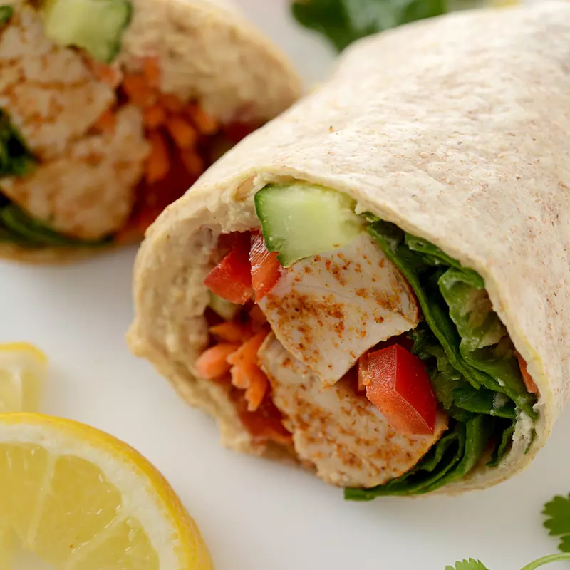 Two halves of chicken veggie wrap with lemon garnish