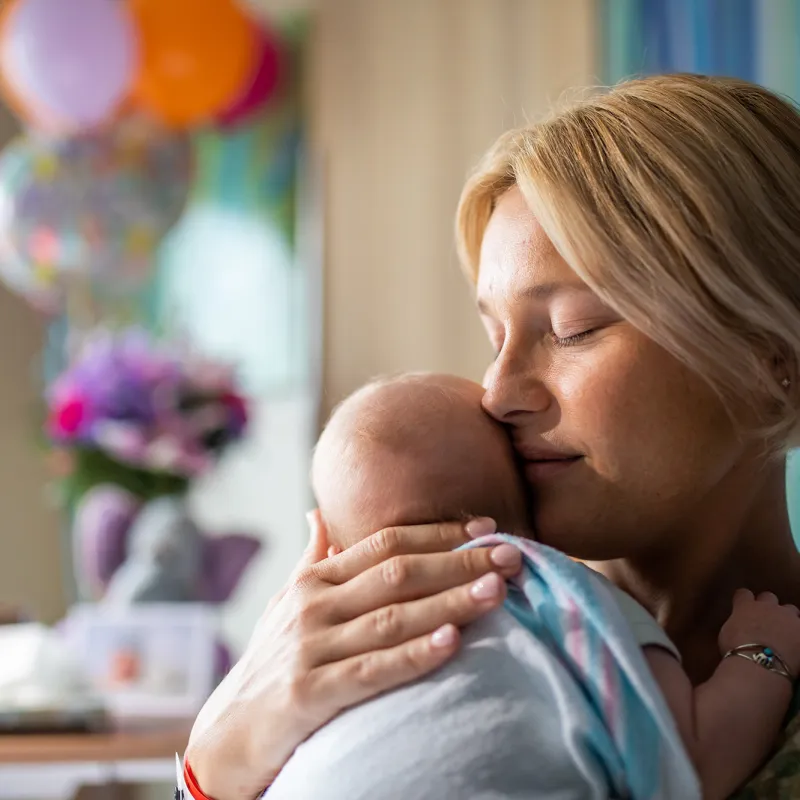 New mom holding newborn baby in hospital room 