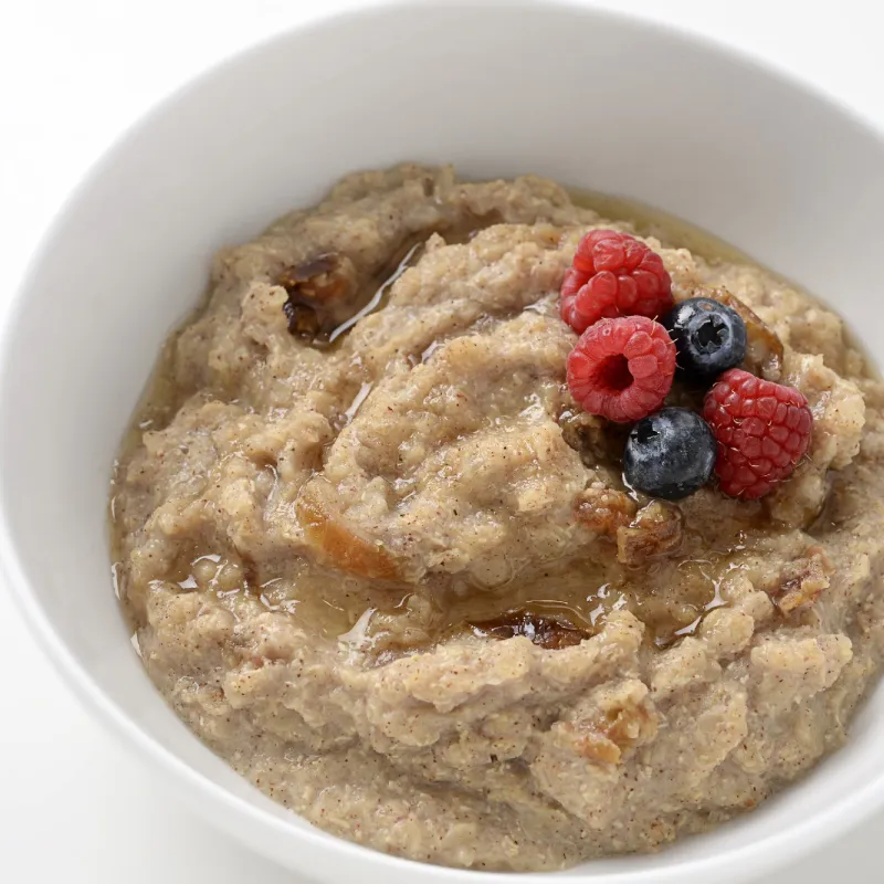 bowl of cooked quinoa, topped with raspberries and blueberries