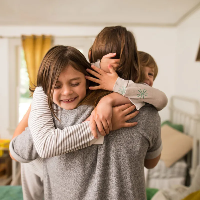 A mom getting warmed hugs from her kids. 