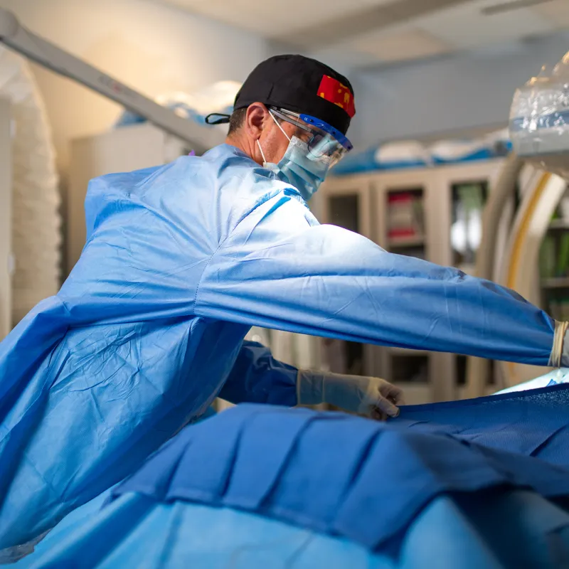 Neurosurgeon placing surgical drape over patient.