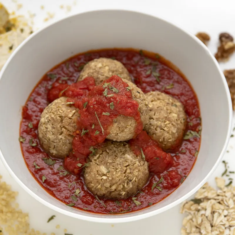 Bowl of nut balls in red sauce with breadcrumb decoration