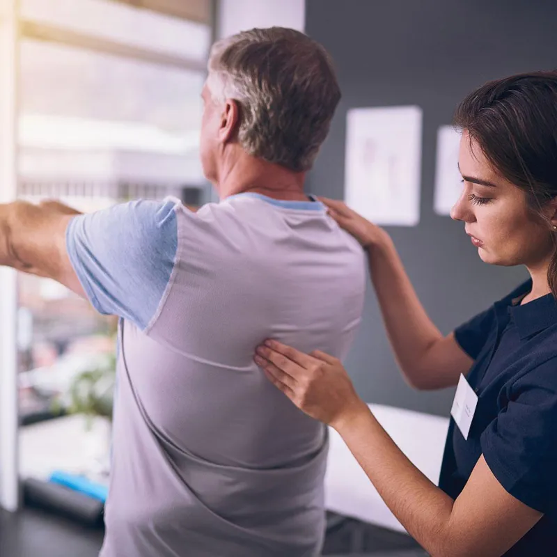 Nurse pressing on back muscle of a rehab patient