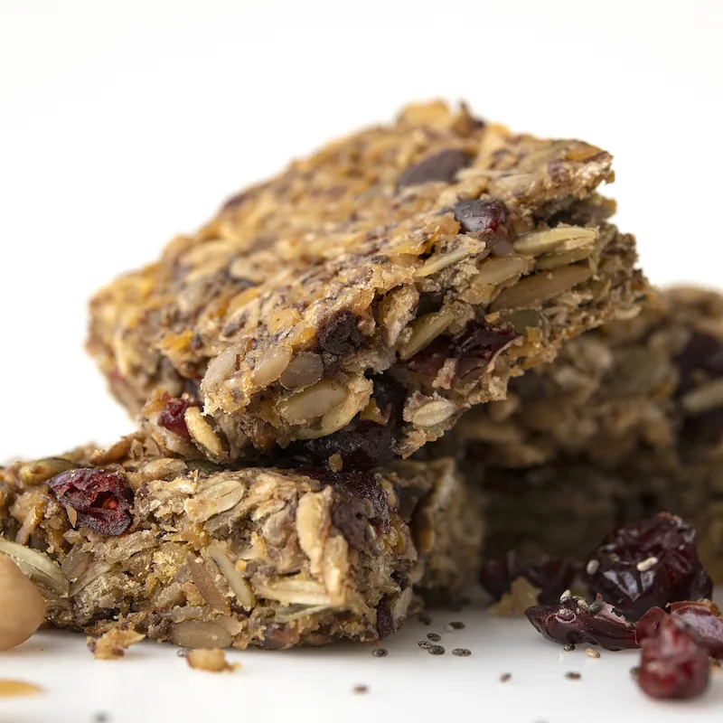 Four stacked square energy cookies next to garbanzos and raisins