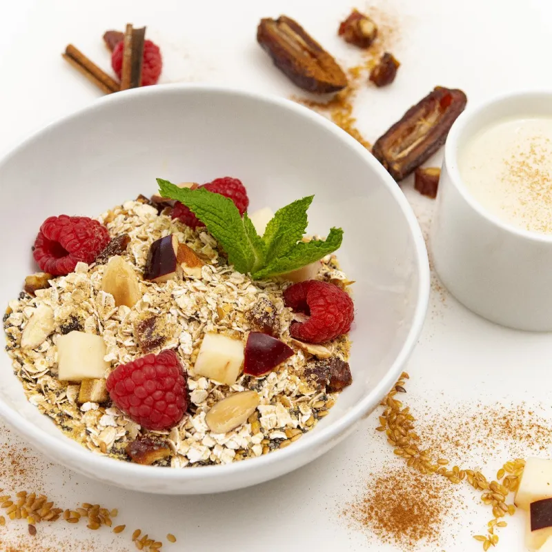 a bowl of oats, topped with fresh raspberries and chunks of apple