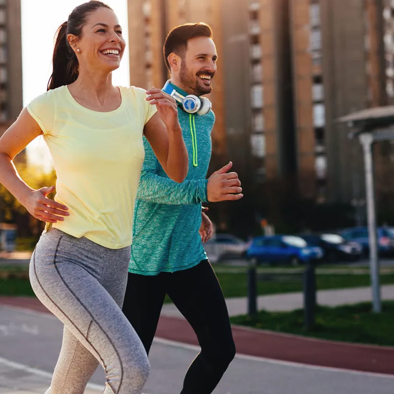 Couple running outside in the city during sunset.