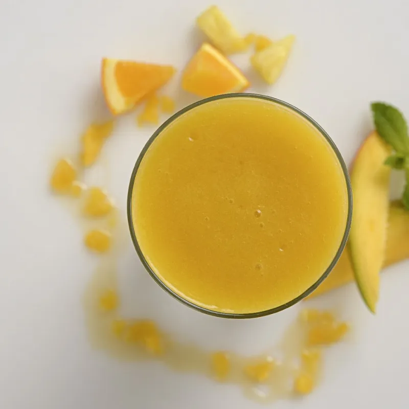 an overhead shot of a clear glass filled with pineapple-mango smoothie