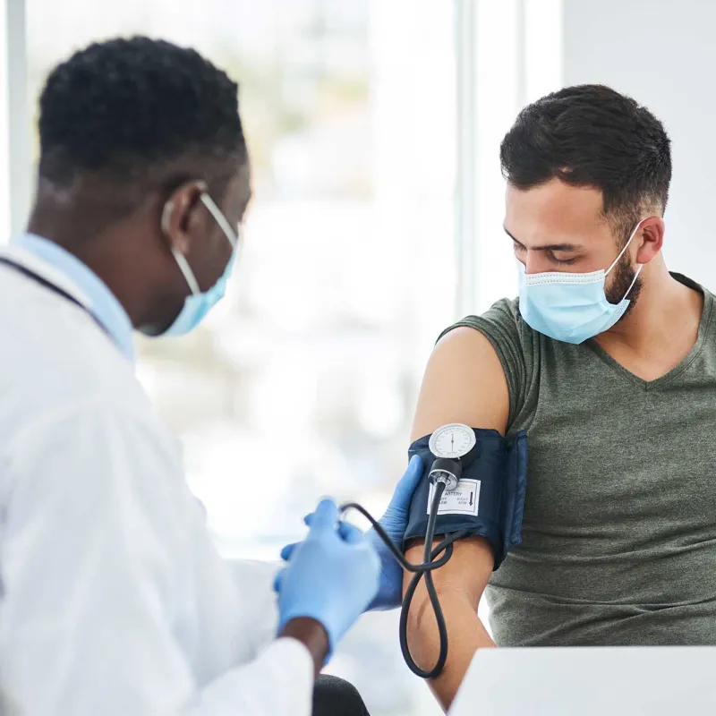 doctor with mask taking blood pressure of patient with mask