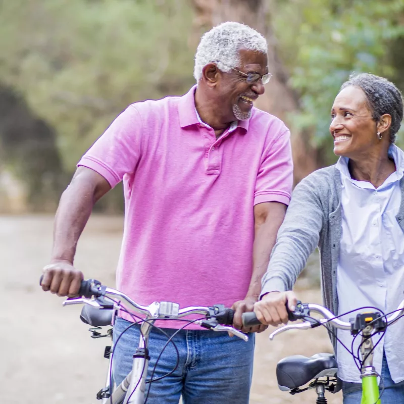 Older couple walking with bikes.