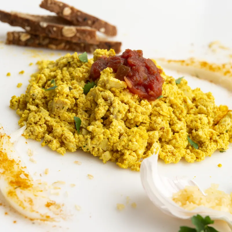 Scrambled tofu on white surface with toast garnish