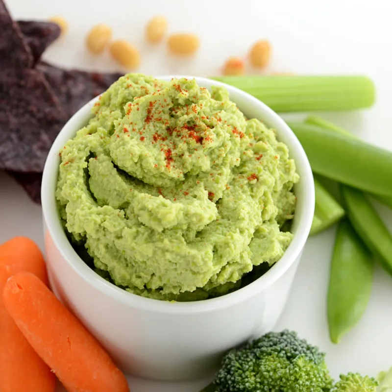 Side dish of edamame hummus with some carrots and chips