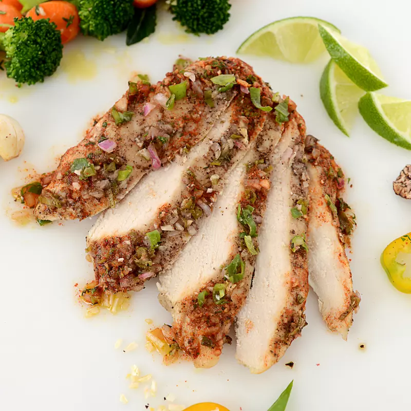 Sliced jerk chicken filet with veggie and lime garnishes