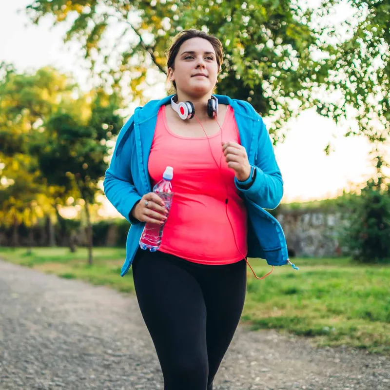 A woman running with headphones and a bottle of water