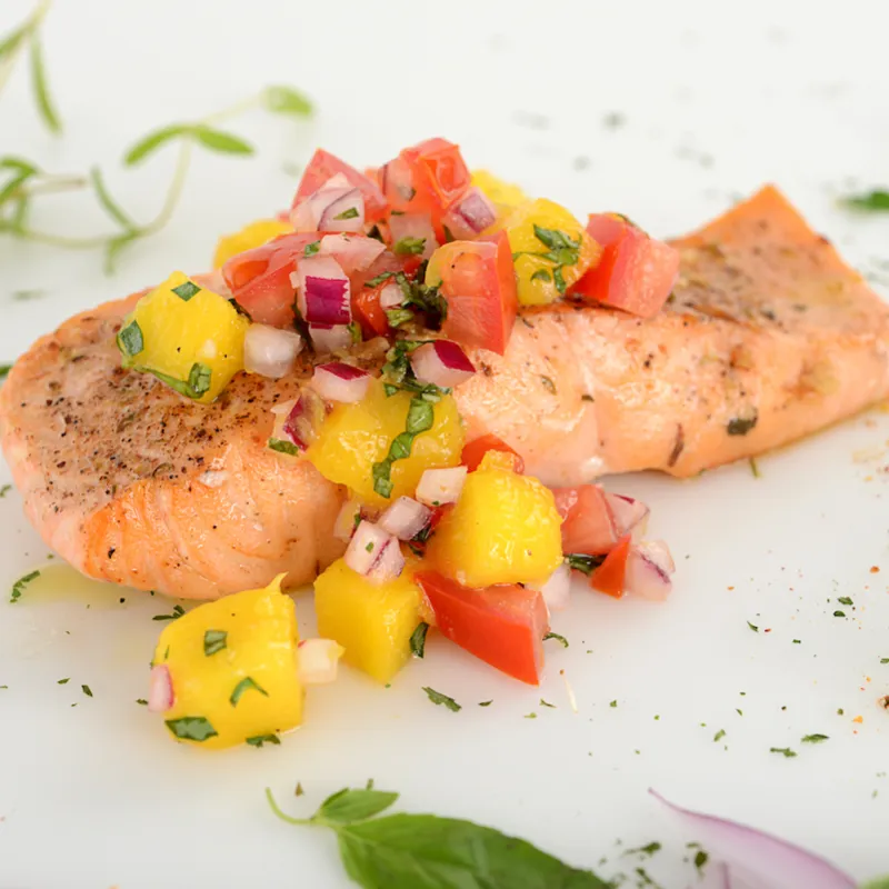 A salmon filet topped with tomato-mango salsa