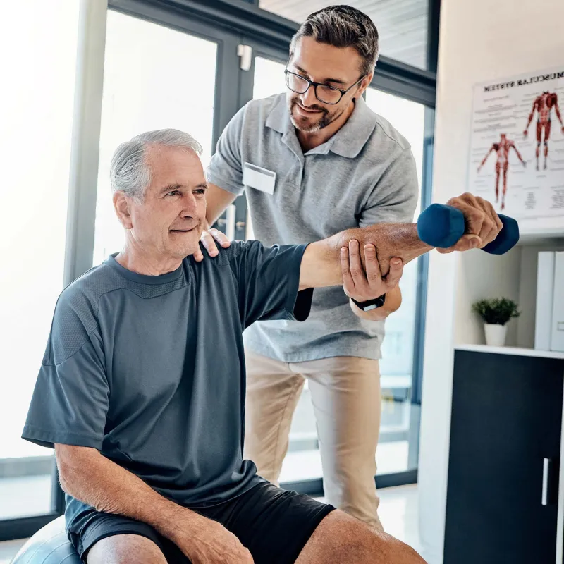 Senior man lifting dumbbell during rehab