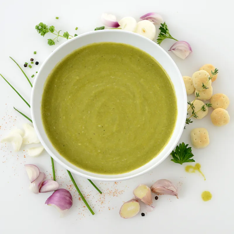 Bowl of asparagus soup with floral decoration beside bowl