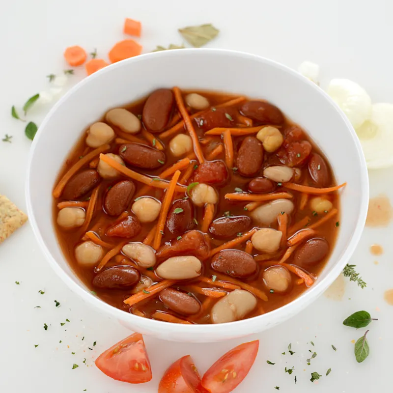 Bowl of Tuscan bean stew with cracker and tomato garnishes