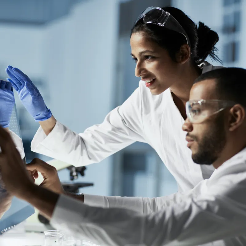 Two lab technicians reviewing results on a computer screen