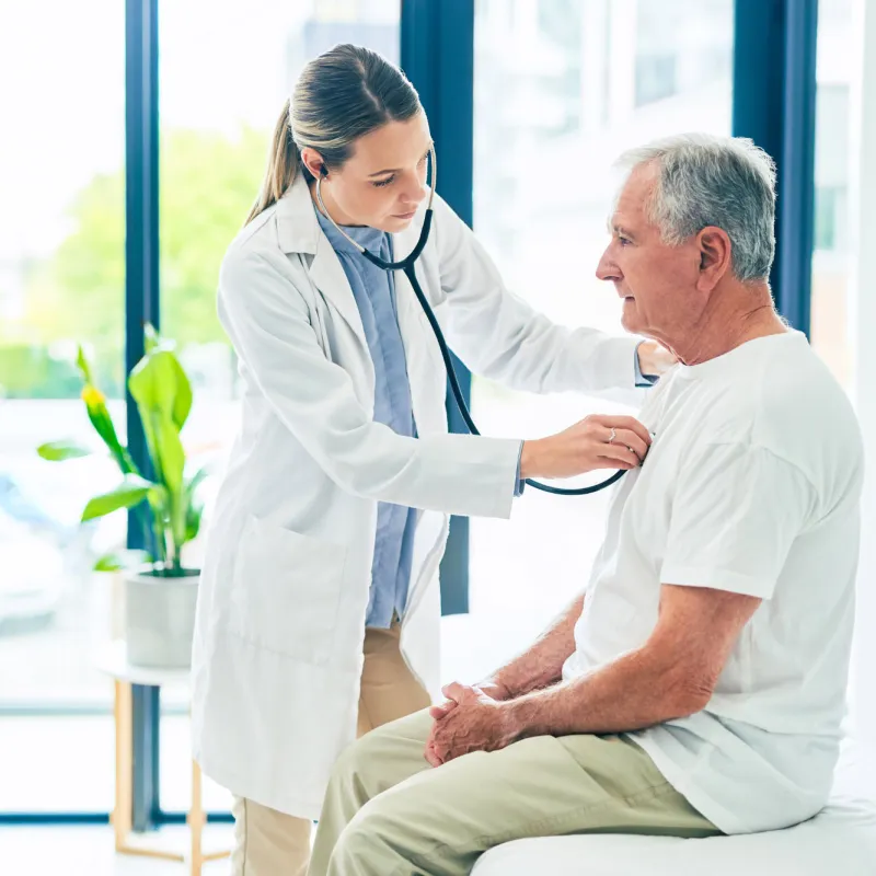 A female physician examining an older man's breathing with a stethoscope. 