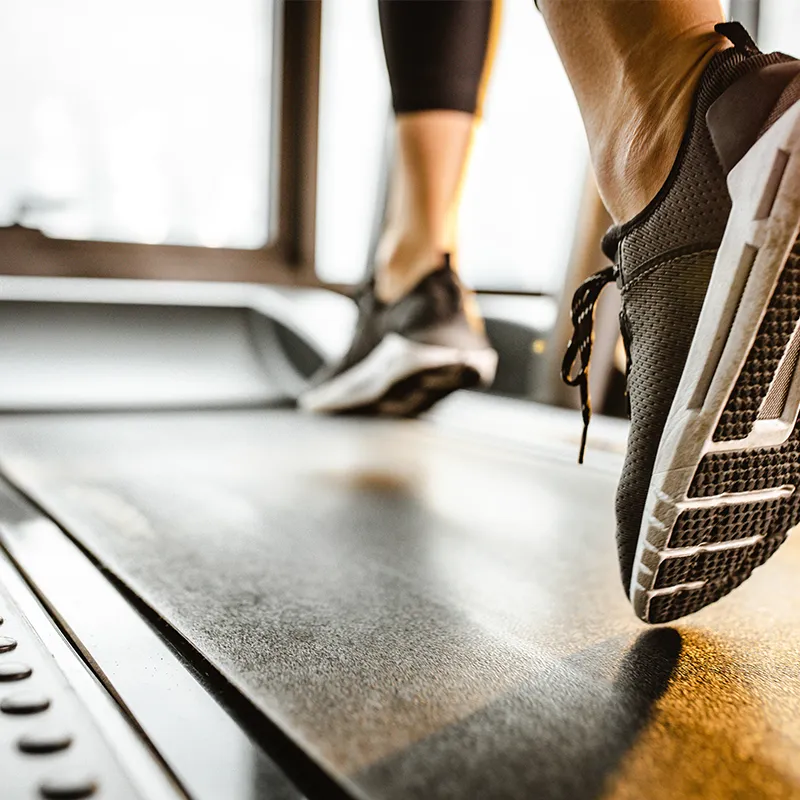 The feet of someone running on a treadmill.