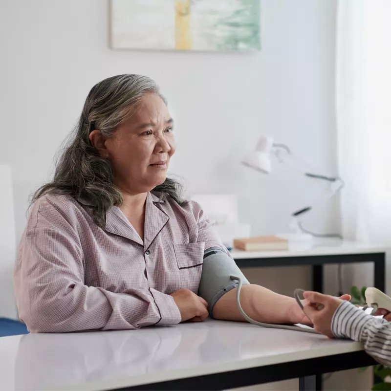 Adult daughter checking senior mother's blood pressure.